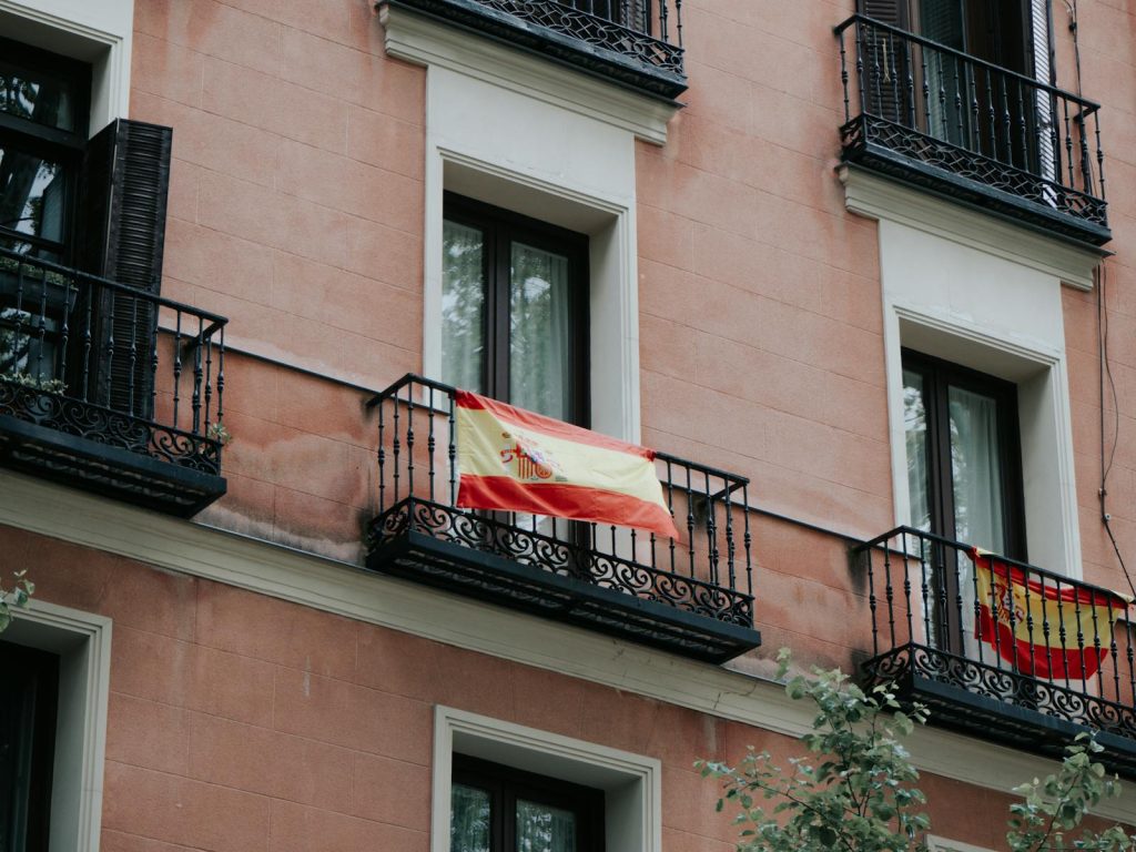Spanish flags displayed on balconies of a residential building in Madrid, Spain.