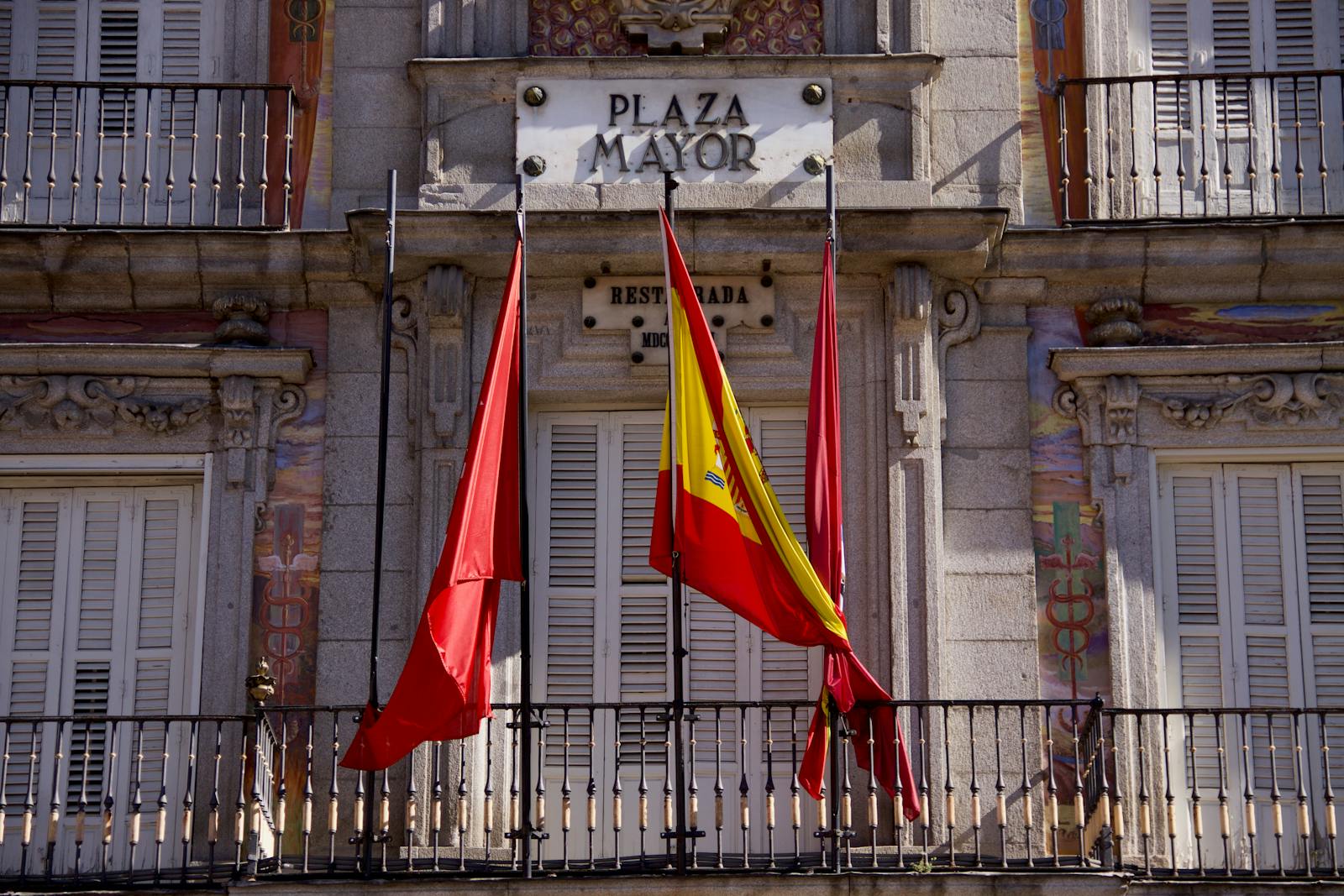 Detailed view of Plaza Mayor's facade with flags in Madrid, Spain, highlighting classic architecture.